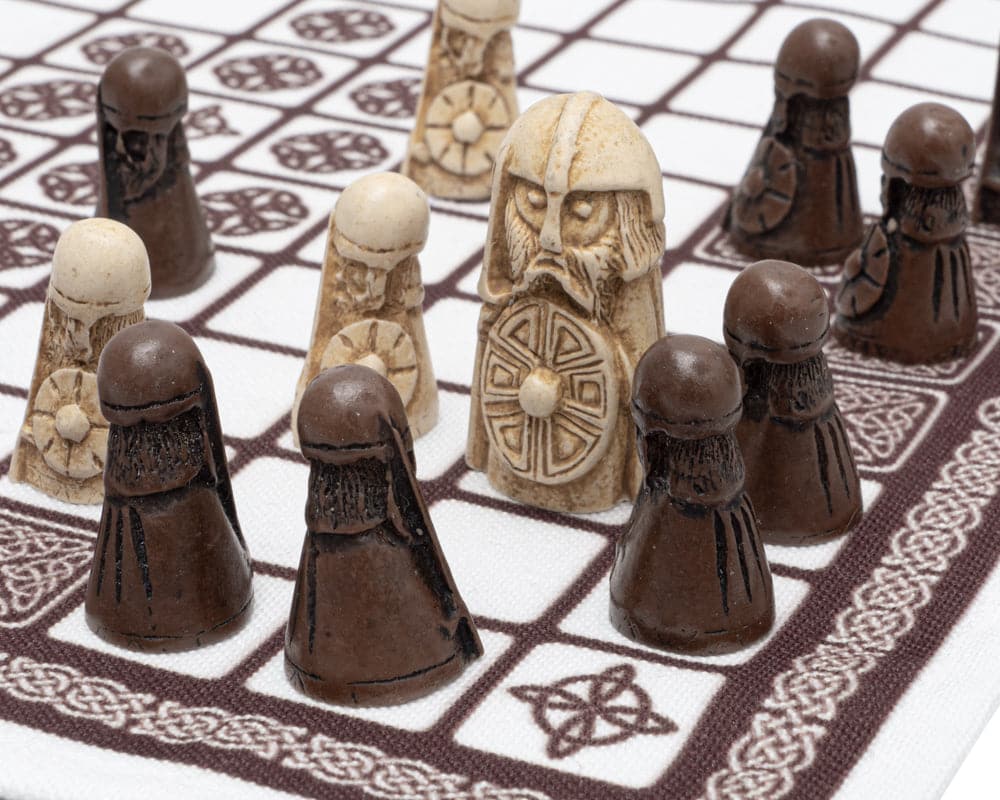 Hnefatafl Viking game pieces on linen playing surface with white King and defenders surrounded by dark attackers