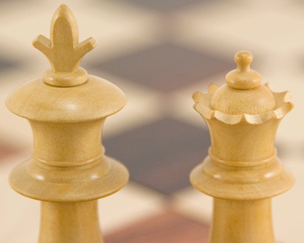 Close-up of ebonised boxwood king and queen chess pieces from the Flower Series Staunton Chess set on a chessboard.