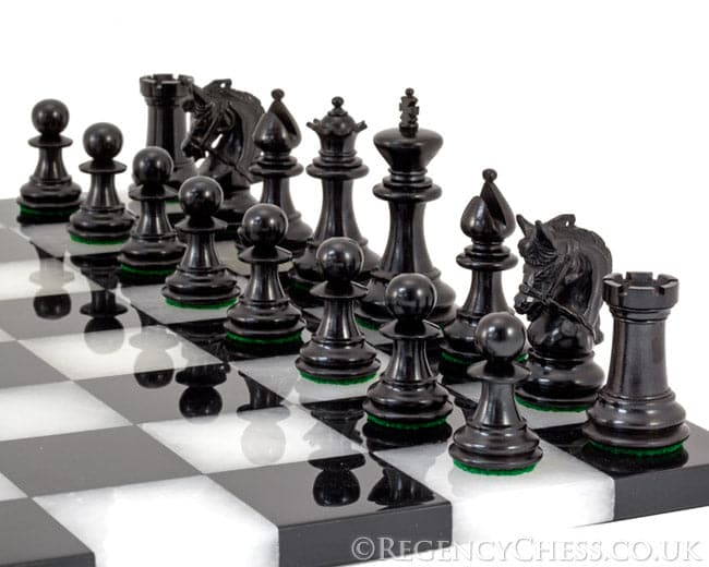 Corinthian Tres Corone Luxury Chess Pieces in black wood on a black and white chessboard, featuring Staunton design and green felt bases