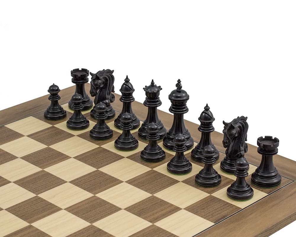 The Kingsgate Ebony Chessmen 4.25 inch set displayed on a wooden chessboard, featuring intricately carved ornate knights and weighted ebony pieces with billiard cloth bases.