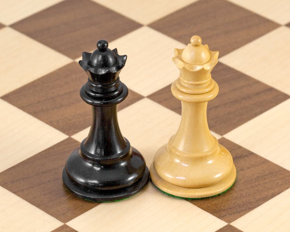 Ebonised black and natural white Staunton king chess pieces on walnut and maple chessboard squares.